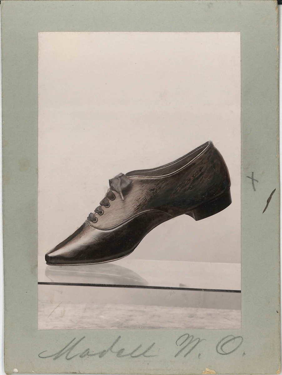 Fotografi av ett skodon. Damsko med snörning. 

Använd som reklam på A F Carlssons skofabrik.

Ingår i en samling med 123 stycken kort i kartong.