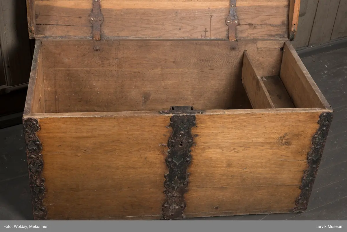 Kiste med buet lokk, rette sider. Leddik til høyre. gj.br. jernbeslag på lokket, i hjørnene og på sidene. Jernhengsler med beslag. Jernhåndtak i sidene