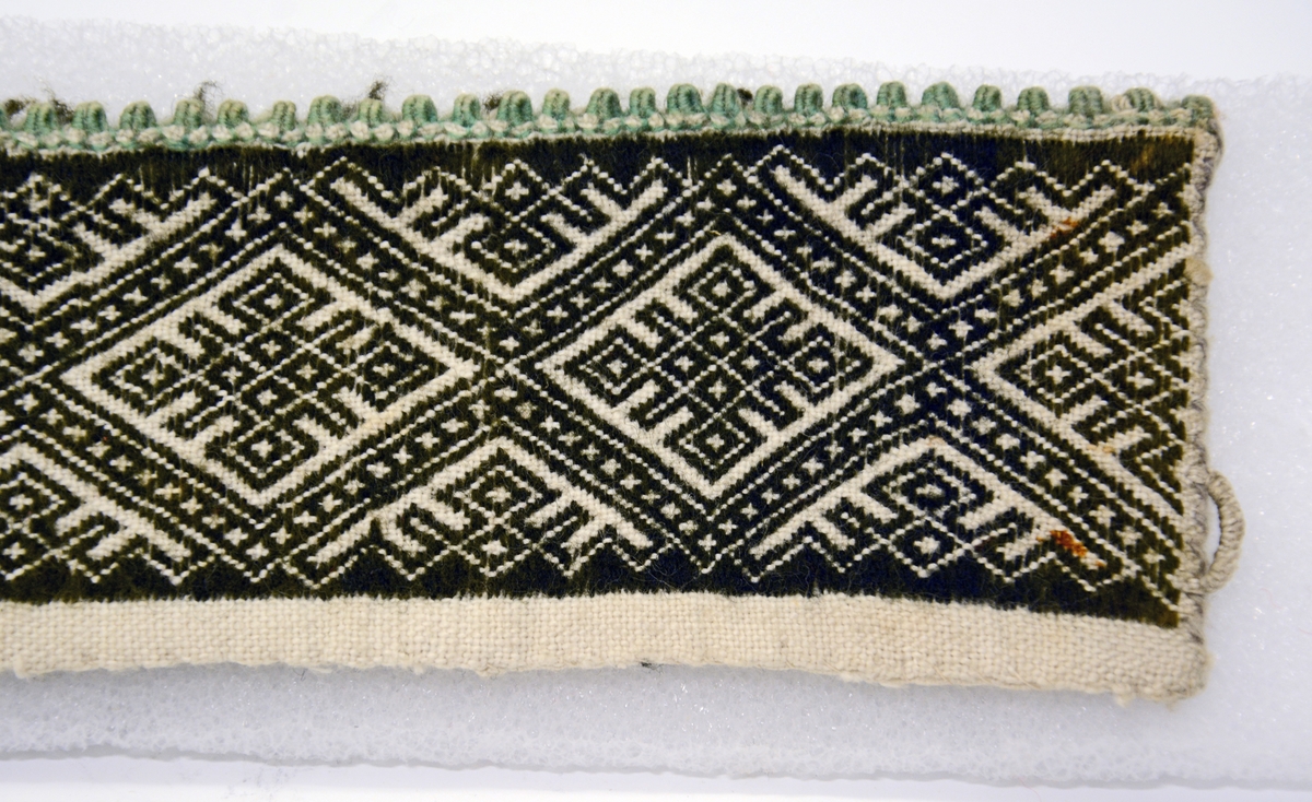 Fra protokollen: 
Kvarde av bomuldstøi med sort smøigsaum i mønster som nr. 1281 (rhombisk bord med fempasrute i midten). Grønne tagger.