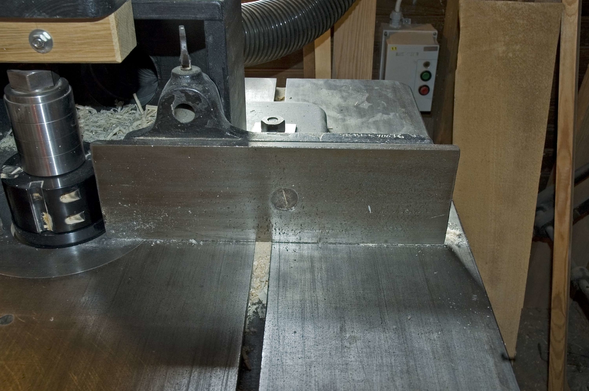 Anhåll av stål för kombinationsmaskin SK:REK 9008. Flytt- och ställbart anhåll som monteras på maskinens matningsbord vid fräsning. Anhållet utgörs av en järnplatta och fästanordning med bult. Kilen i fästanordningen skall modifieras för att passa T-spåren på fräsmaskin SK:REK 9061. Fräsfunktionen på kombinationsmaskinen används ej. Längden kan variera efter önskemål genom skruvning.

Funktion: Stöd vid fräsning