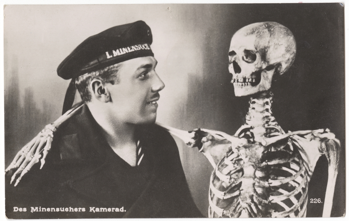 Tyskt vykort från första världskriget: flottist på minsvepare med skelett. Text: "Des Minensuchers Kamerad." (Minröjarens kamrat)