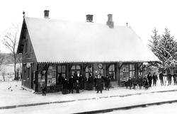 Råde jernbanestasjon med reisende passasjerer i vinterdrakt.