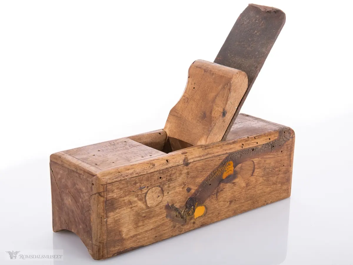 Liten rektangulær høvel med jern og kile. Konkavt u- formet spor i sålen.
