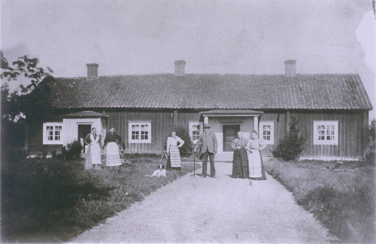 En familj framför en parstuga i Fliseryd.