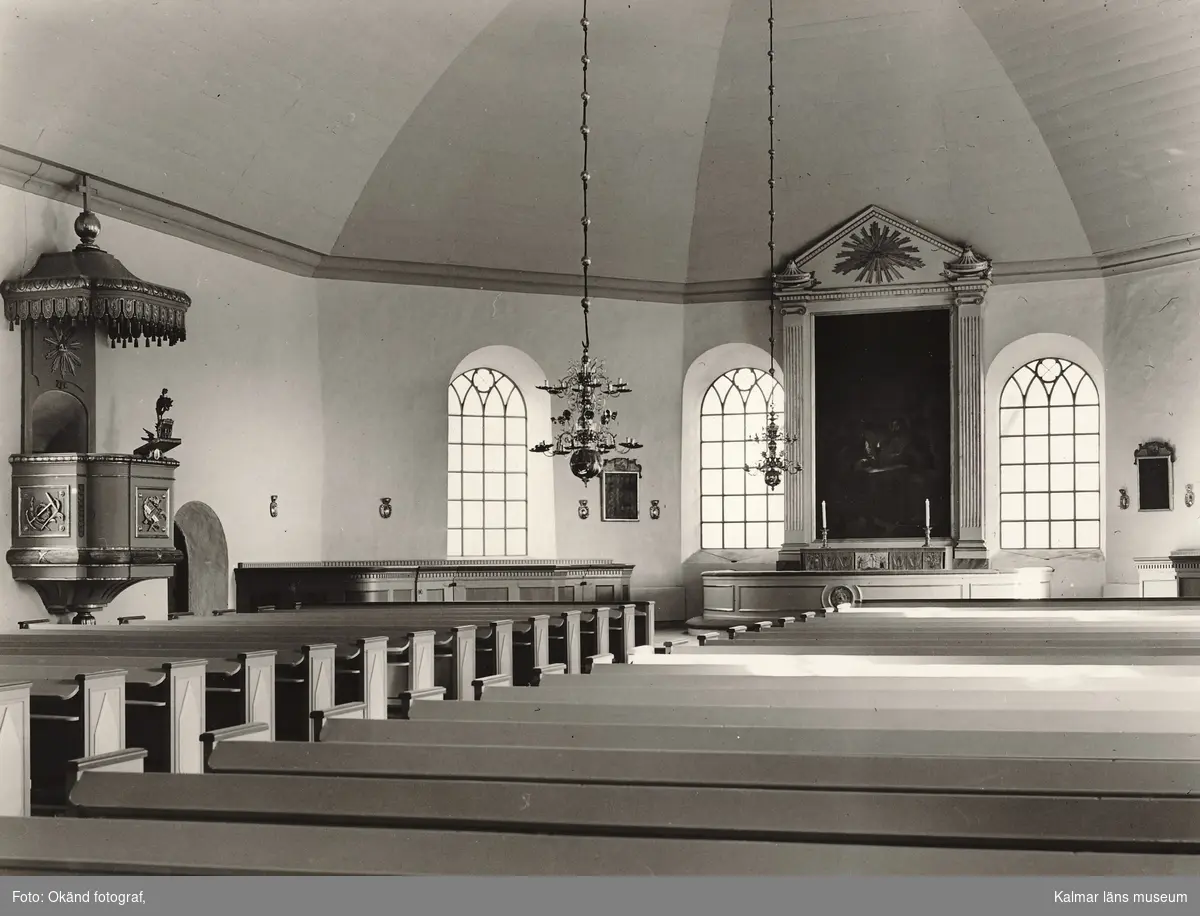 Interiör från Odensvi kyrka med prediksstol, altartavla och bänkrader.