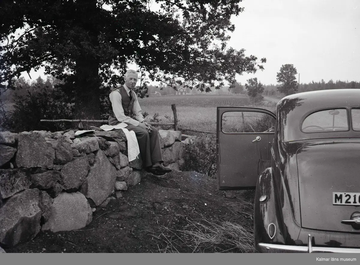 Man som sitter på stenmur. 1938 Ford V8.