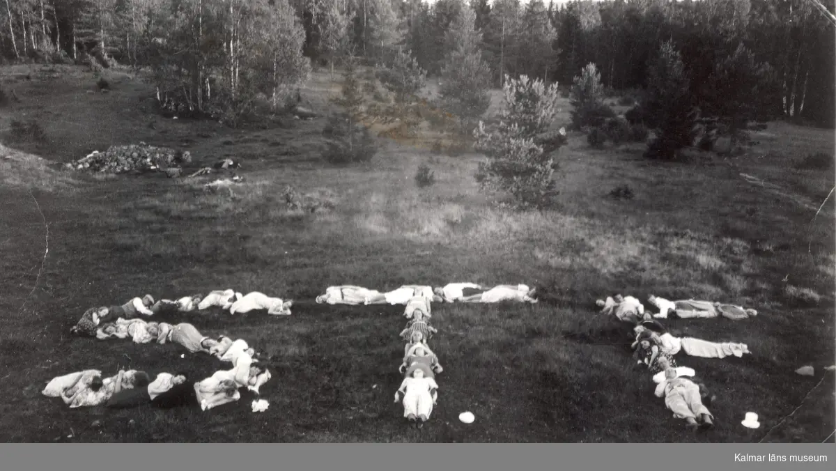 Amatörfoto av ett antal människor, som ligger utsträckta på marken tillsammans bildande bokstäverna STF.