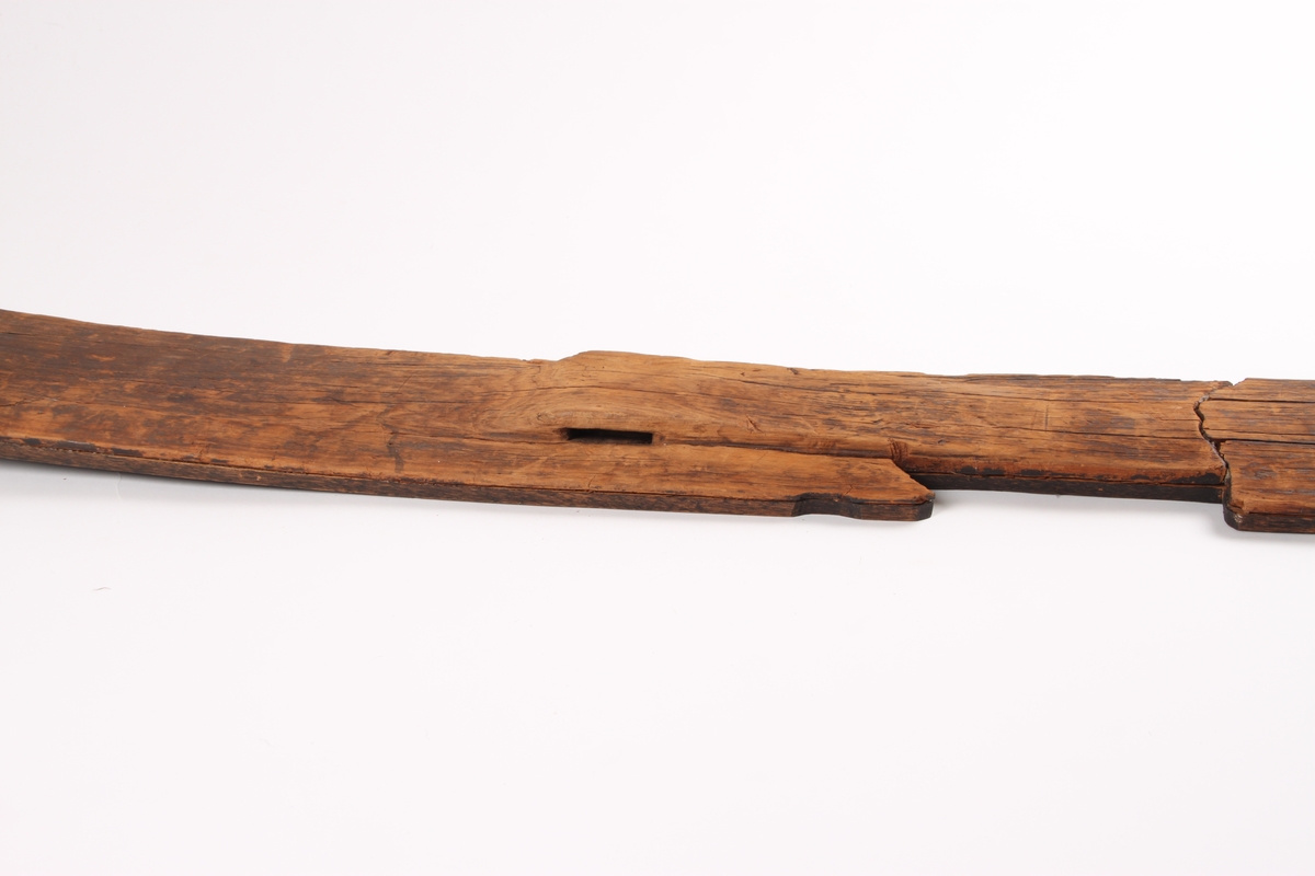 En ski med en lett krummet form og spiss i begge ender. Omtrent midt på skien er det en opphøyning i treet hvor det går et horisontalt hull gjennom skien til å feste bindingen i. På hver side av fotstegplaten og bindingsfestet går det en bred kant. Oversiden av skien er flat, med en noe buet overflate på den ene siden av skien. På undersiden av skien er det påmontert en treplate formet etter skien. Platen er festet med skruer. Skien har to grunne styrerender.