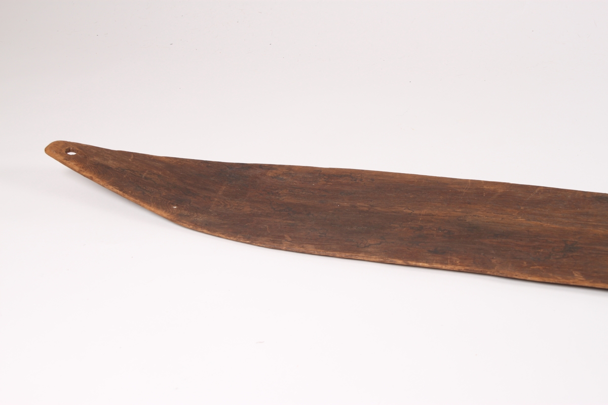 En enkelt ski med svakt møneformet rygg både på fram- og bakski. Skiens tupp er brukket av, mens bakskien ender i en spiss. Det går et hull gjennom bakskien. Skiene er bredest bak. Underside er flat uten rand.