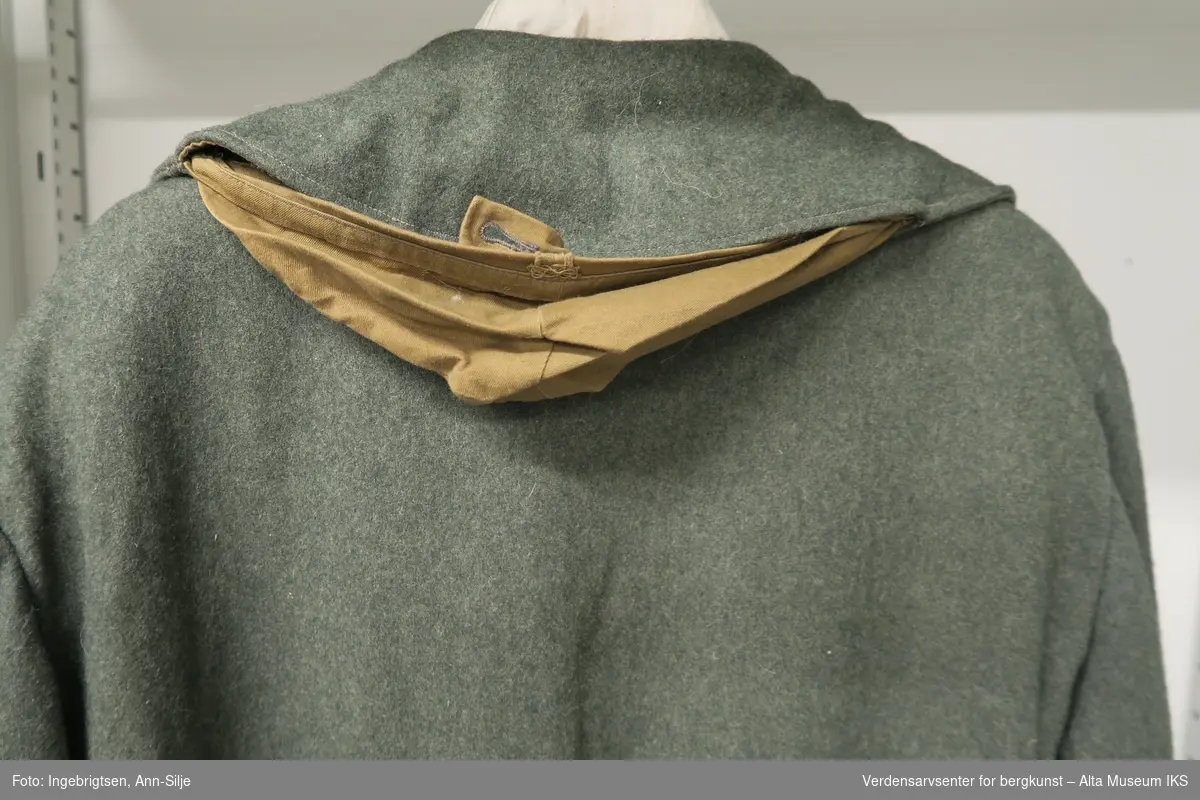 Dobbeltspent jakke med saueskinnsfor. I kragen er det innfelt hette i tøy. Knappene har relieffer av anker - emblemet til den tyske kriegsmarine.
