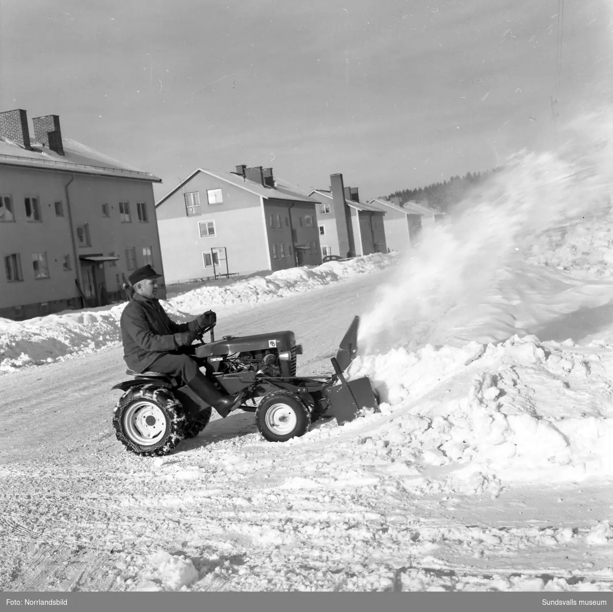 En man röjer snö med en Wheel Horse, en liten traktor med snöblad och slunga, på Vikingavägen i Granlo.
