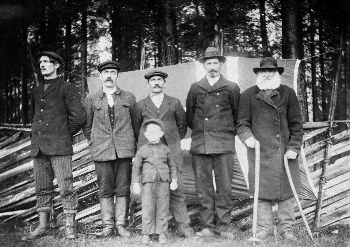 Gruppe på 5 menn stående foran et gjerde i Støa med et flagg bak seg. En gutt står foran dem. 
Fra venstre: Petter Opseth (1889 - 1934), Petter Kjellbak (1881), Peter Støa (1873 - 1955), Petter P. Smed (1868 - 1954), Jan Petter Svensen (1823 - 1913). Foran: Petter Persen (Støa) (1908)