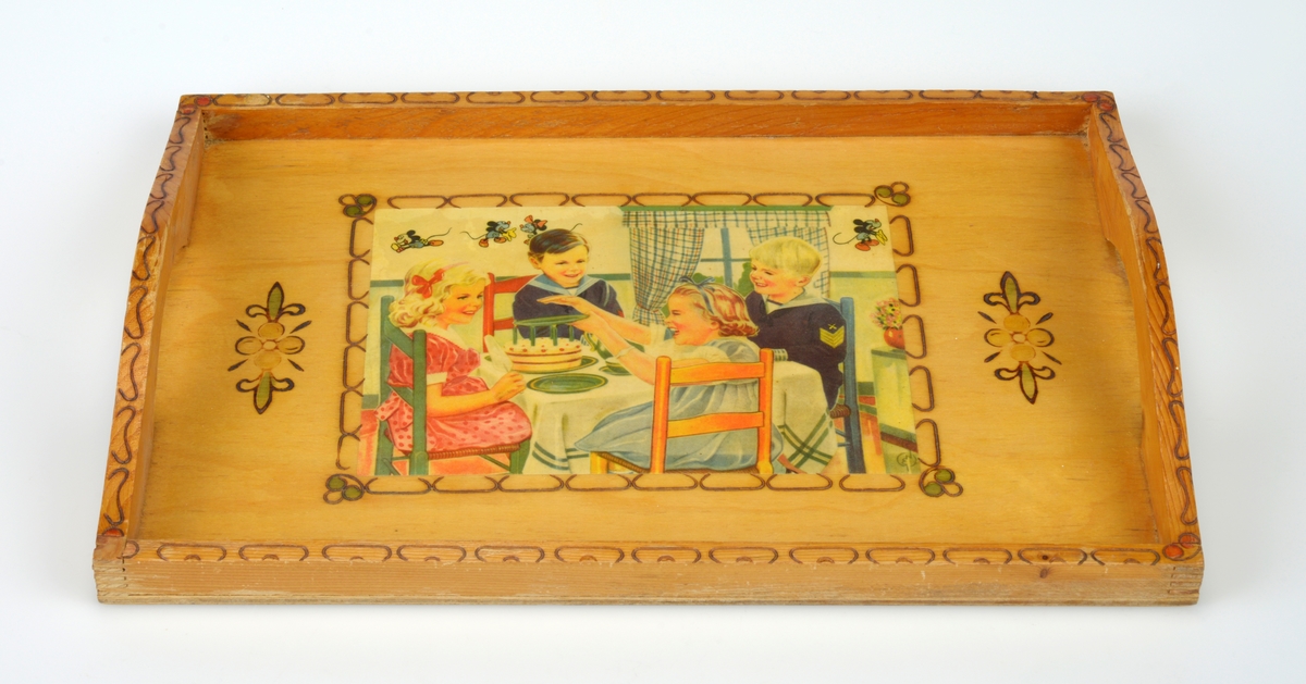 Et firkantet serveringsbrett laget av kryssfiner og tre. Flaten er kryssfiner og på midten er det limt på et trykk (papir) som er lakkert. Motivet er to jenter i kjole og to gutter i matrosdress som sitter ved et bord. På bordet er det kake. På veggen i rommet de sitter i er det små figurer som er Mikke Mus og Minnie Mus (den eldre versjonen av figurene). Rundt bildet er det en bord gjort ved svidekor. På hver side av bildet er det en bloms som er malt og svidd. Det er en kant av tre rundt hele brettet. I siden er denne kanten noe høyere og buet. Det er også skåret ut slik at det er håndtak i hver side. På kanetn er det svidekor, og i hvert hjørne er det malt i svidekoren (røde rundinger).