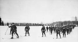 Menn, uniform, ski og skistaver, naturforhold. 
Hele kompan