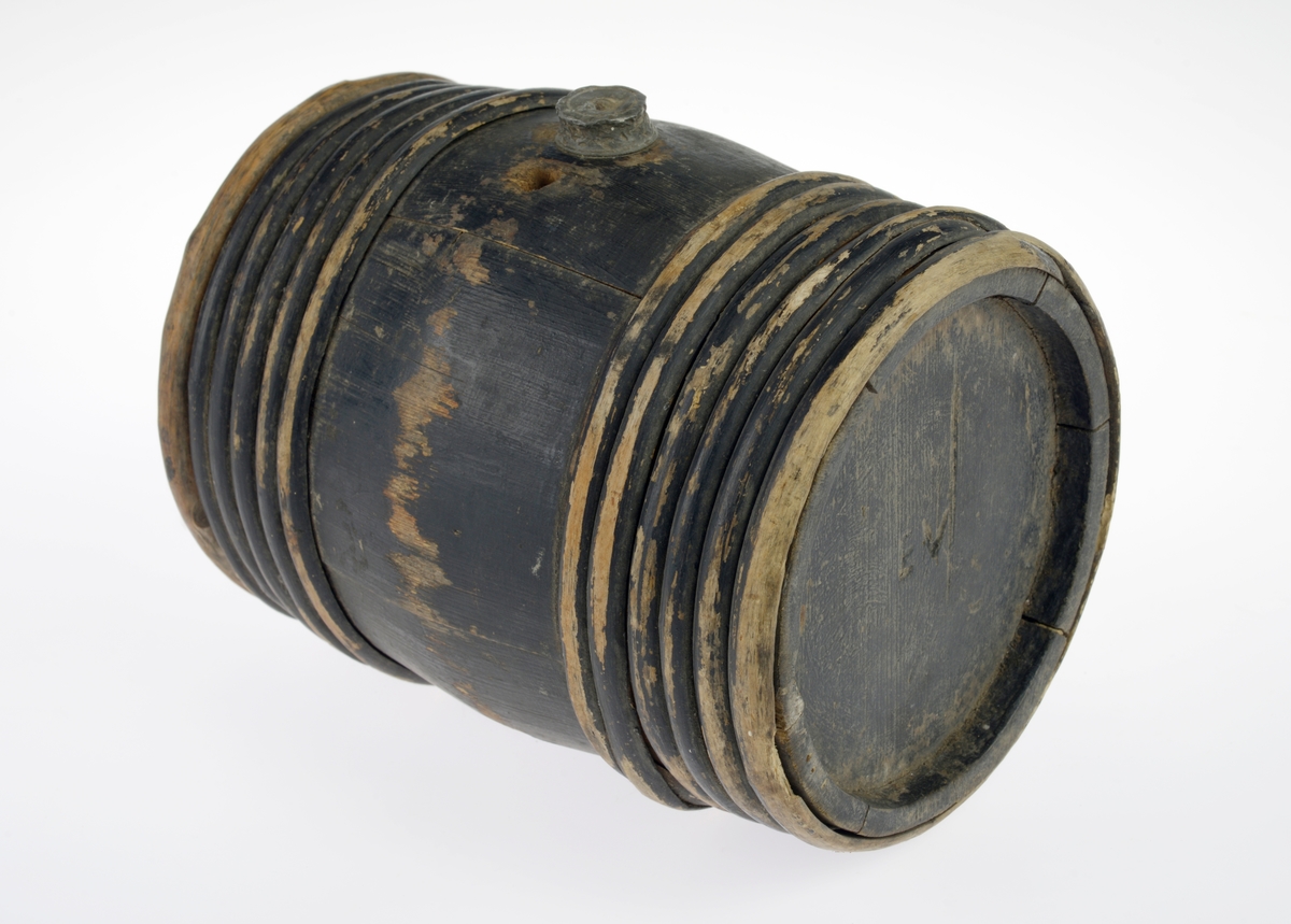 Av gran, lagget, malt svart, med 6 vidjebånd på hver ende. Tut og skrukork av bly på soden, og et mindre hull ved siden av tuten.  Innskåret på ene bunnen: "EV".