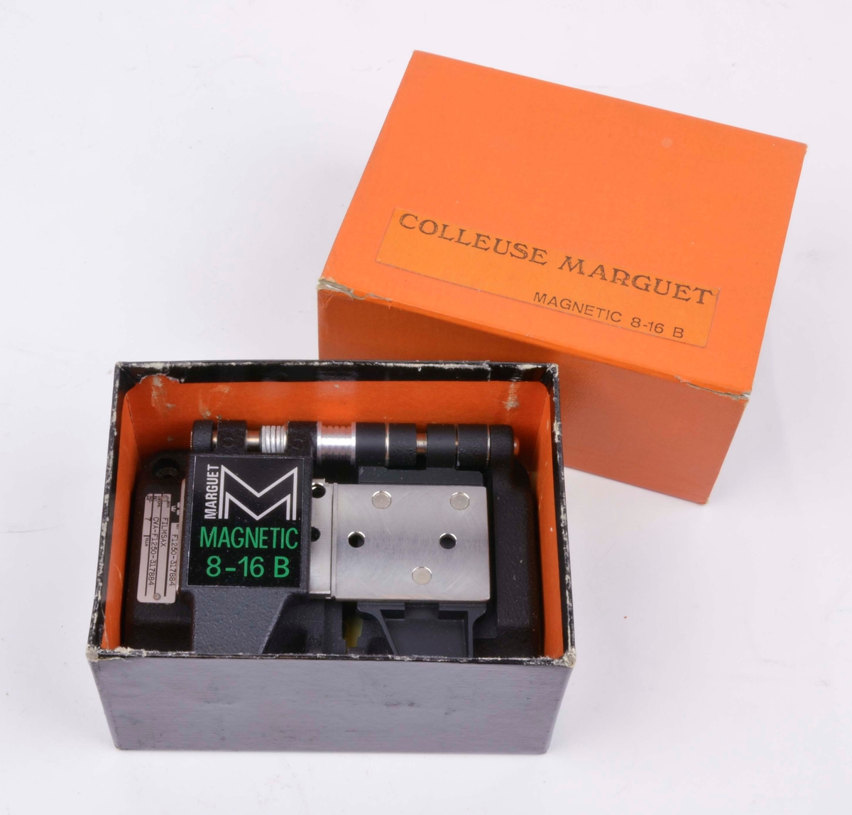 Filmsax av märket Marguet Magnetic 8-16 B. Filmsaxen ligger i sin tillhörande ask som är orange och har inskriften Colleuse Marguet Magnetic 8-16 B.