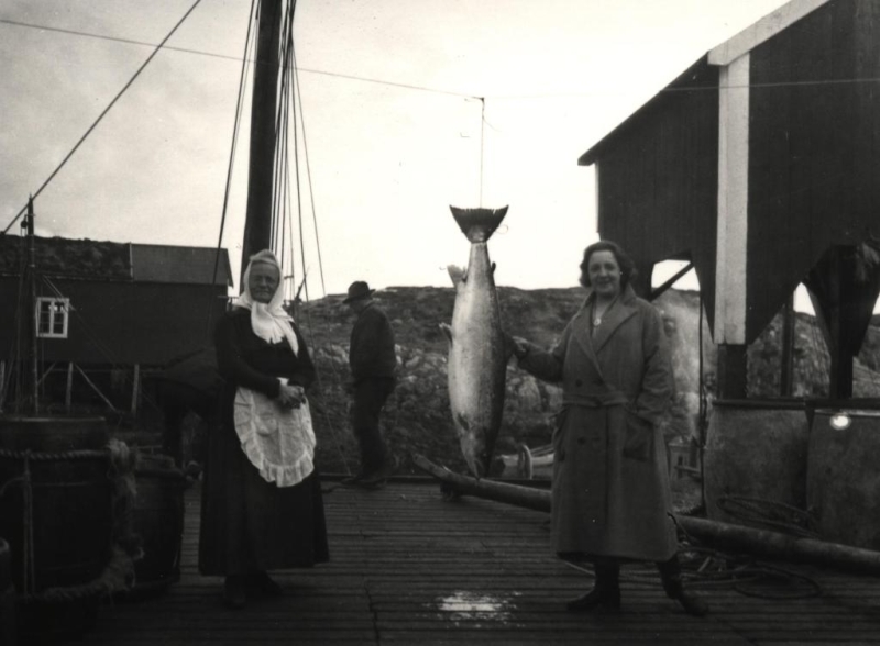 To kvinner med en fisk på kaia i Åsvær