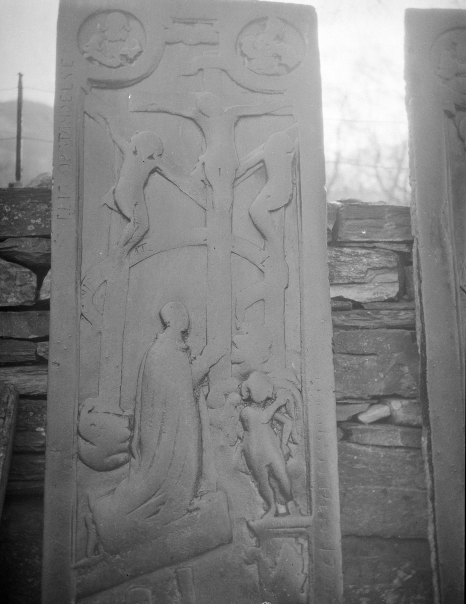 To steinplater med relieffer oppreist ved steinmur antagelig på kirkegård, religiøst motiv