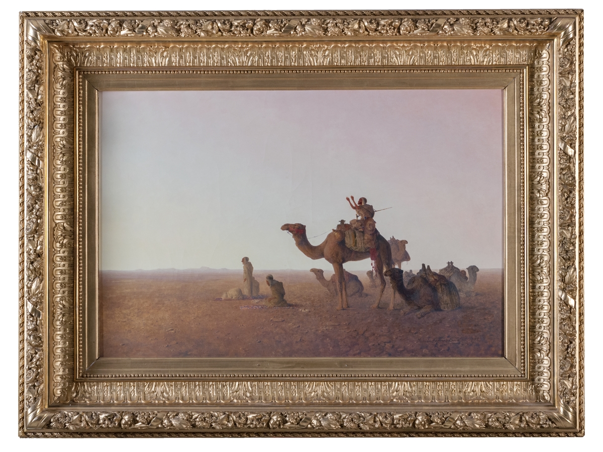 Fem bedjande muslimer med sina kameler i öknen. Vid bön ska man som troende muslim knäböja på marken. Mannen som sitter kvar på kamelen har en krycka och är troligen handikappad. Därför behöver han inte knäböja vid bön. Förgylld ram.