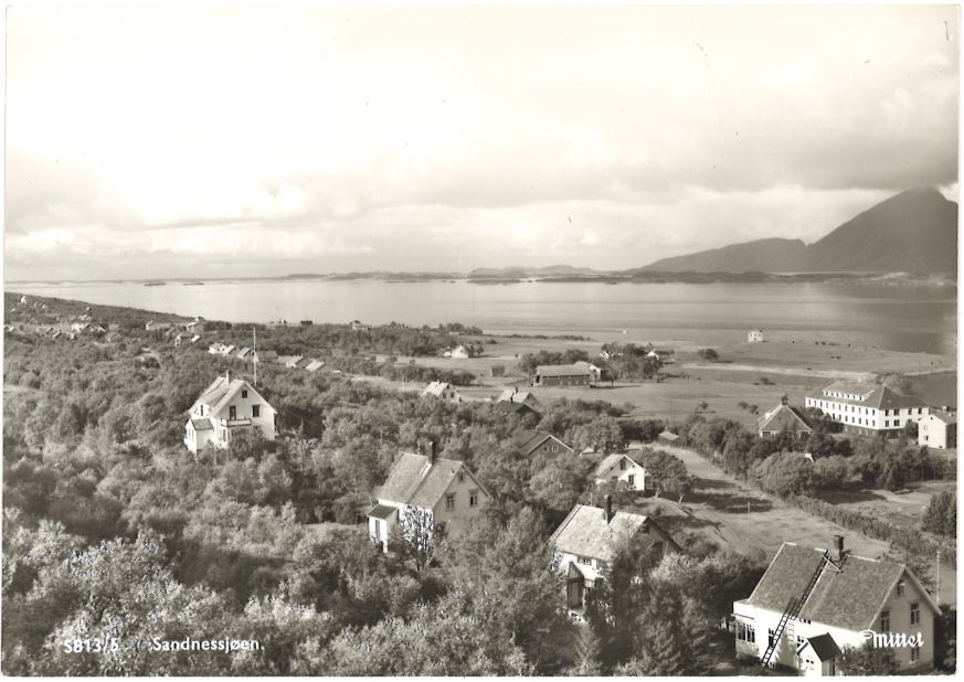 Svart/hvitt foto. Sandnessjøen, med hus og søsterhjemmet, fra øst-sørøst, med Dønnamannen i bakgrunnen.