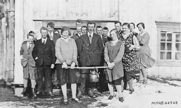 Gruppebilde. Personer foran hus, to med kaffekjele. Møte og 