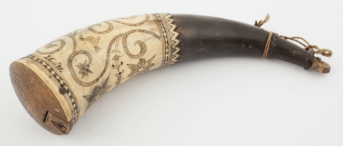 Krutthorn med bunnplate i tre med luke. Ornamentikk på horn i form av blomster, ranker, fugler og bårder.