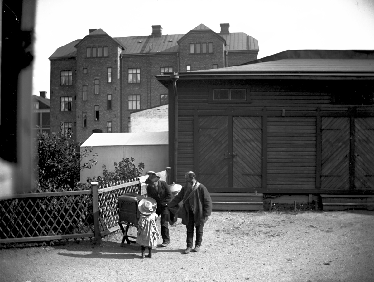 Stadsvy, två män och ett barn i förgrunden.