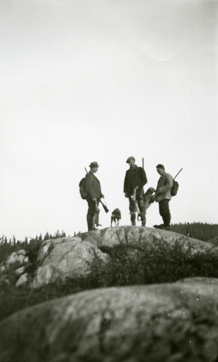 3 menn og hunder stående på en stein. På jakt i Galåsen. 
Fra venstre: Ingvar Galaasen, Jons (3/8 1880 - 1969), P. A. Galaasen (Pauls) (5/12 1887 - 1952) og P.M. Galaasen (Rud), Martins (6/1 1900 - 1994)