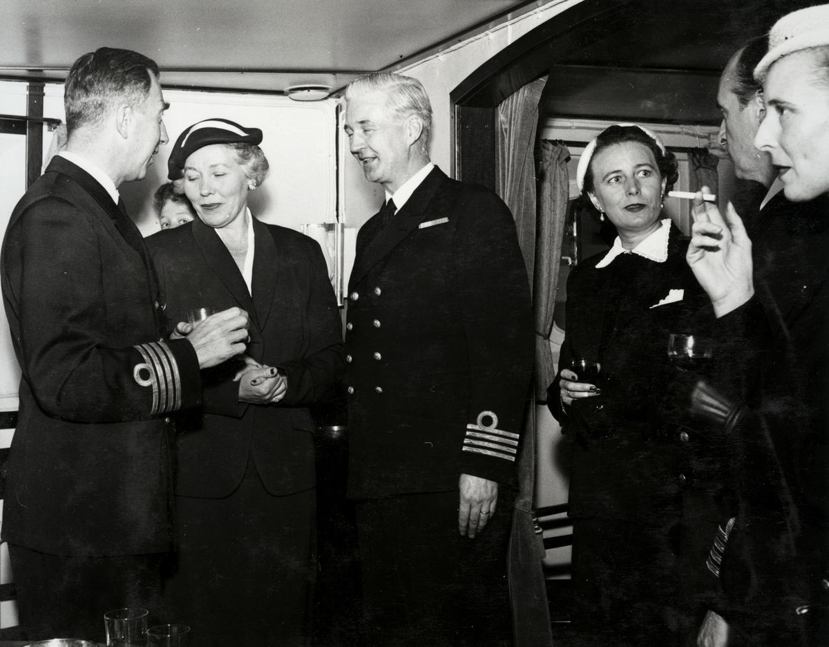 Tre kommendörkaptener av första graden på besök med några damer i kaptenens hytt ombord på Älvsnabben. En av männen är kommendörkapten av första graden Lind af Hageby.