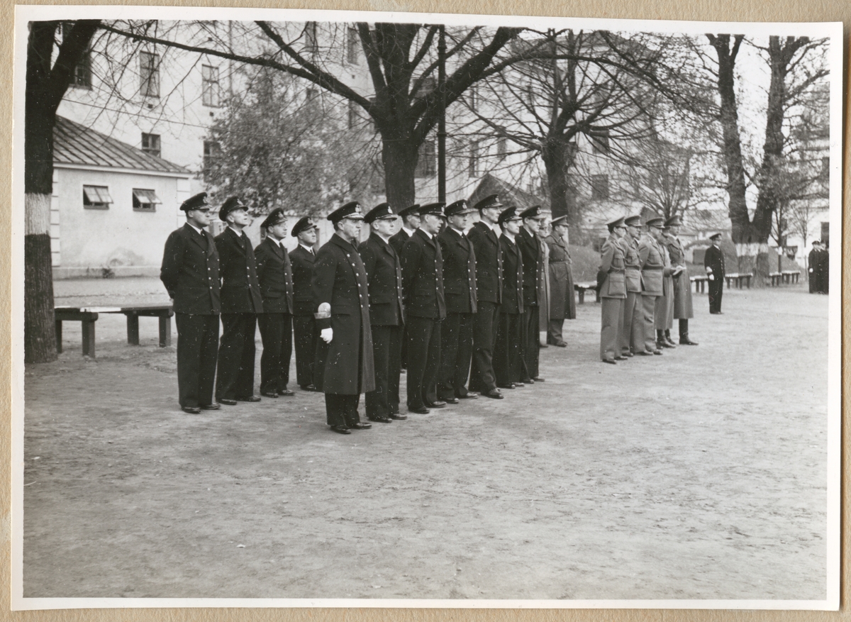 Uniformsklädda militärer av högre rang, bland annat en vice amiral, står uppställda på Sparres kaserngård. I bakgrunden syns kasern Sparre.