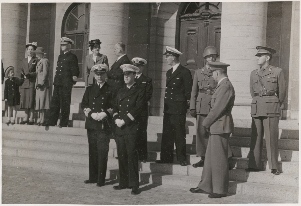 Uniformsklädda militärer ur armén och flottan står på rådhustrappan i Karlskrona. Vid sidan av dem står även en mindre grupp uppklädda civilpersoner.