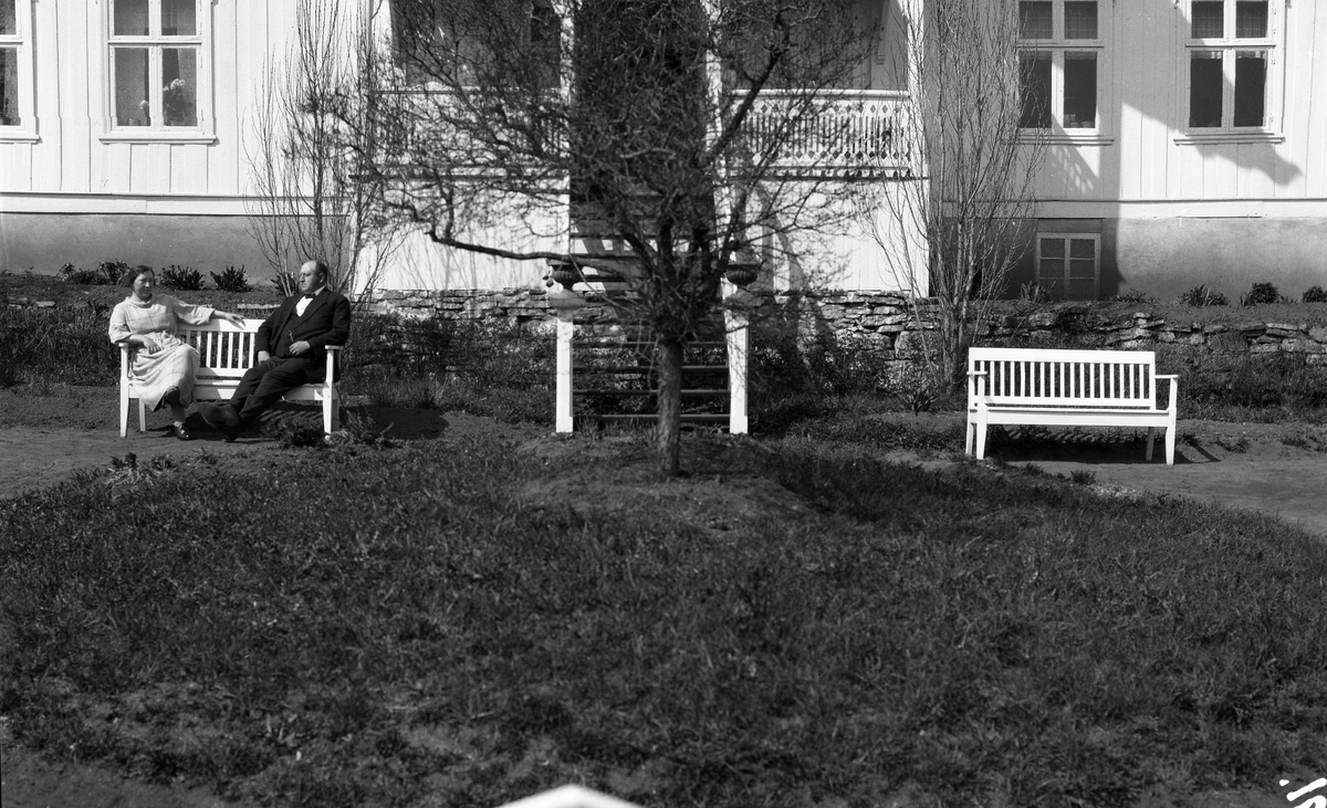 Uidentifisert kvinne og mann foran et våningshus. Fire bilder. På et er kvinnen alene, ellers de to sammen.