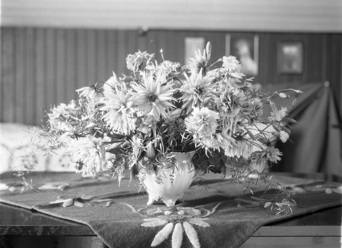 Karine Røisli ved et bord med blomster i en vase.
Tre bilder der to kun viser bordet med blomstene.