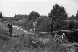 Tre personer på ei klopp, trolig over Lenaelva i nærheten av