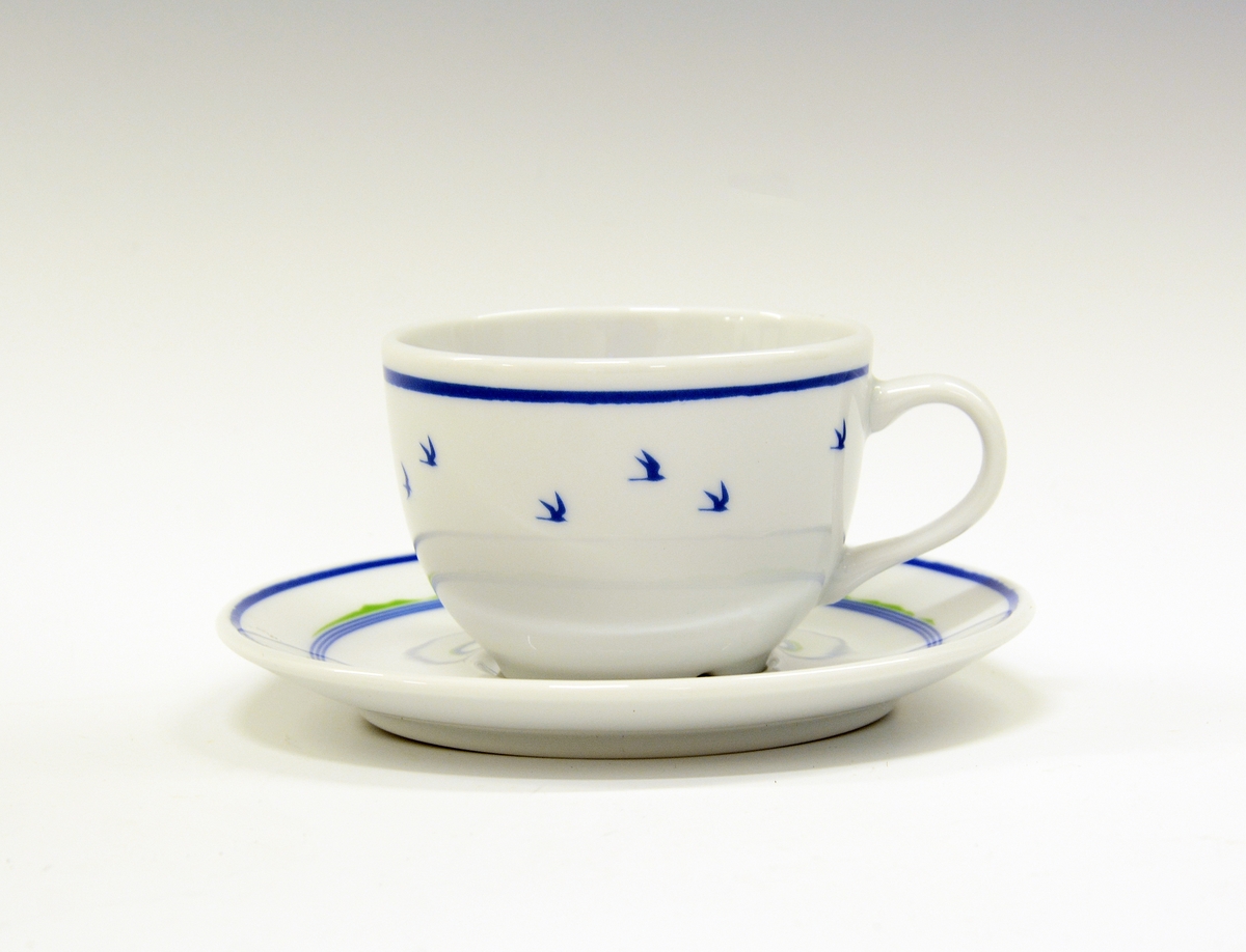 Kaffeskål av porselen. Hvit glasur. Dekorert med blå stripe ytterst på fanen og tre smale blå striper med noe grønt på innerst på fanen.
Modell: Roma