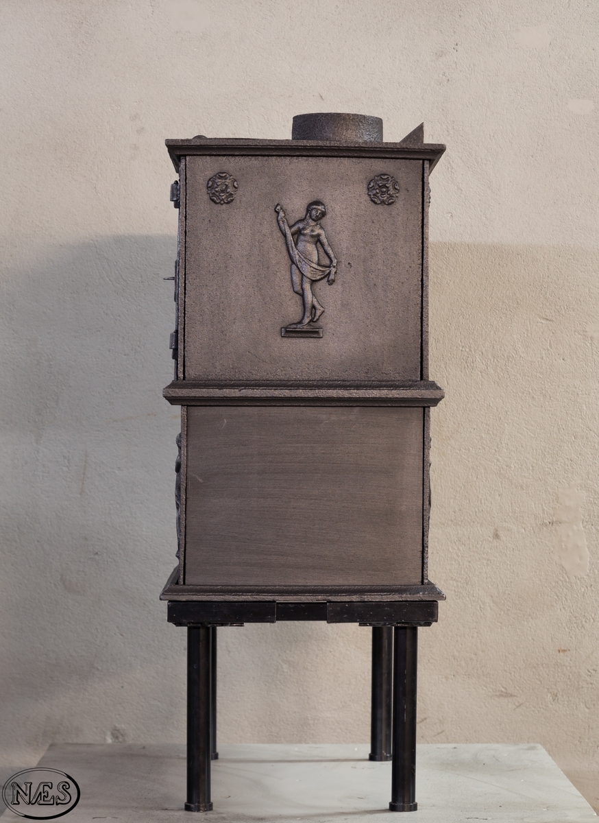 Kokeovn i to etasjer med eget fyrkammer og kokerom. Kokerommet kan åpnes med to dører på langsiden og med en luke i topplaten. Ovnsdøren til fyrkammeret er på kortsiden 1 etg. På langsidene i 1. etg er det tre muser og en engel med lette draperier på en enkel profillist. På kortsidene 2. etg er det draperikledd dansende muse på enkel profillist med en rosett i hvert øvre hjørne. Langsidene i 2.etg er dekorert med en rosett i hvert øvre hjørne.