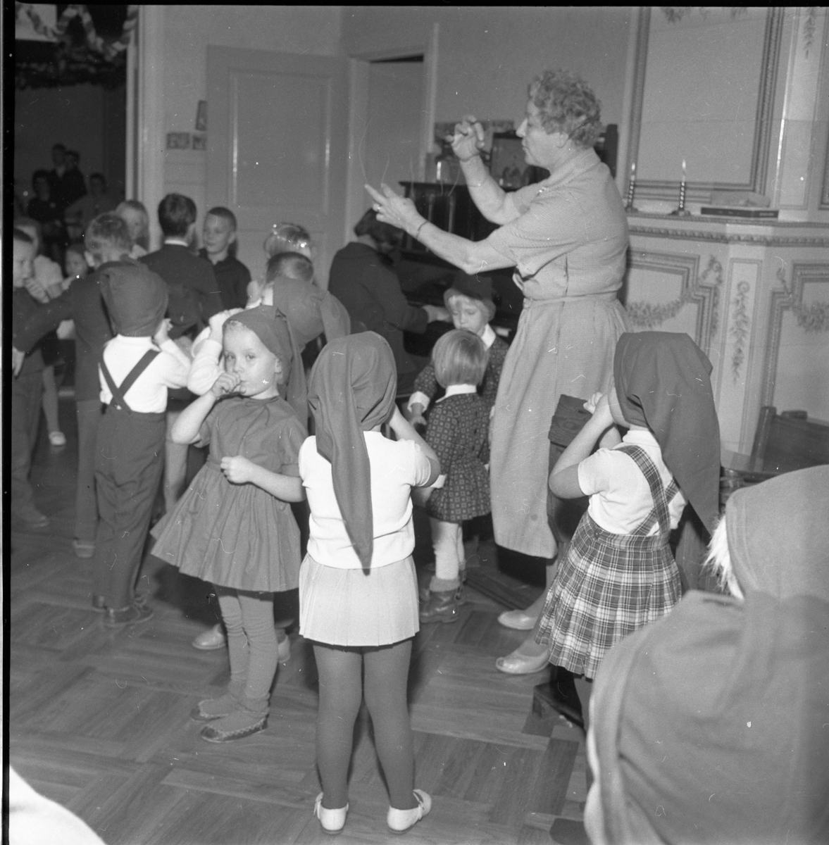 Lekskolan i Gränna, jultid 1963. Okända barn i med tomteluva. Kvinnan är Anna-Lisa "Nalle" Lundin.