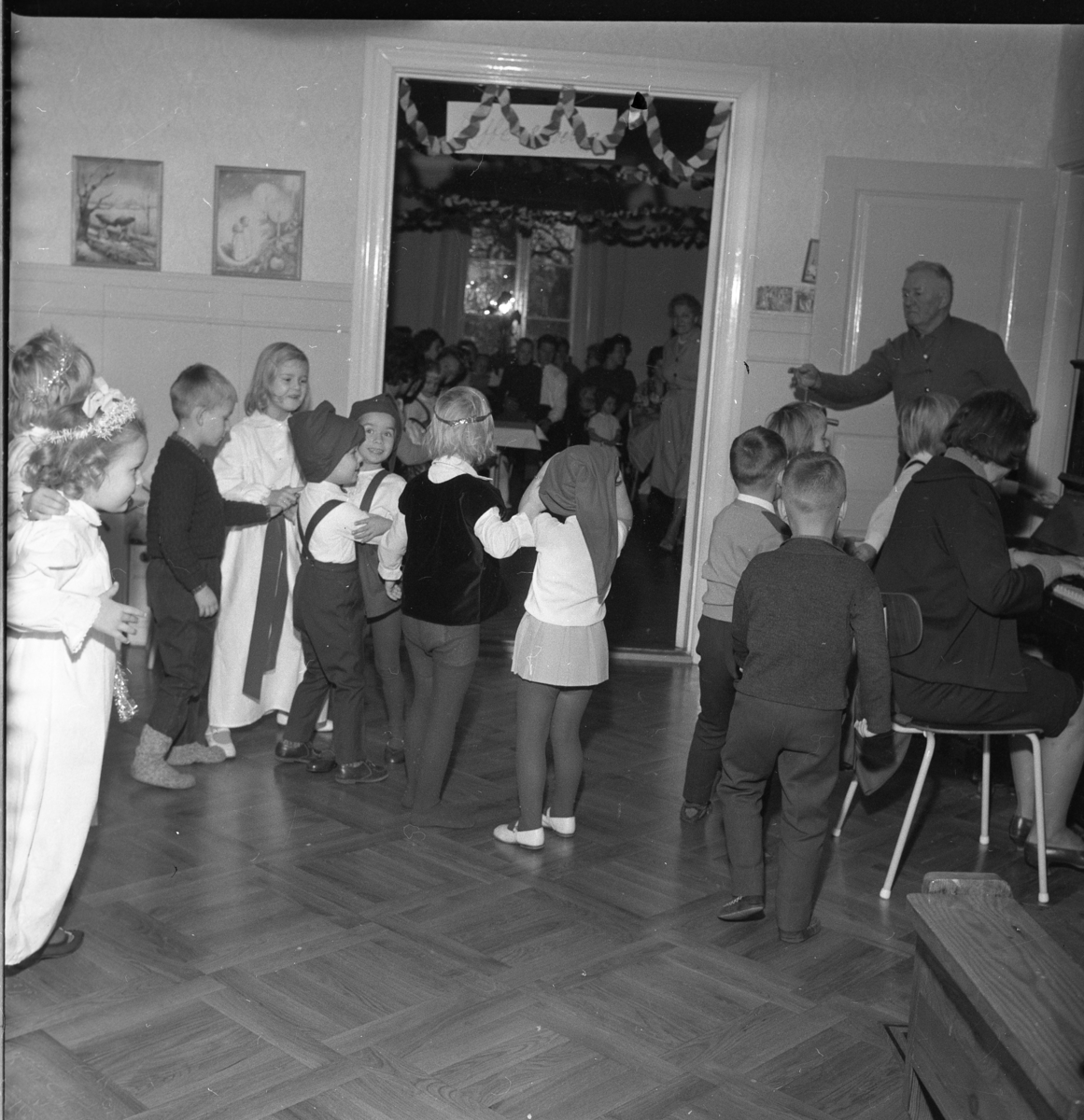 Lekskolan i Gränna, jultid 1963. Okända barn i lucialinne och tomteluva.