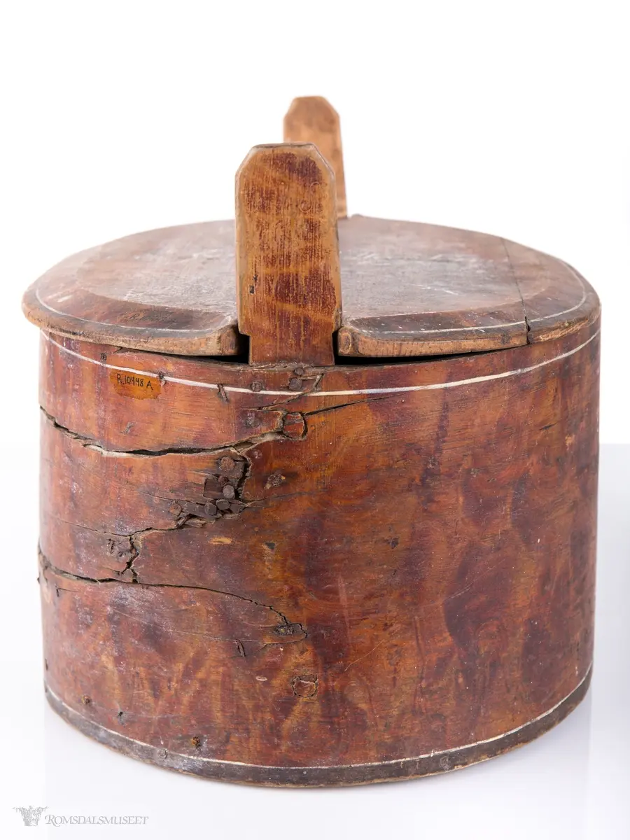 Hvite linjer langs kanten. Avrundet lokk. Innskrift.