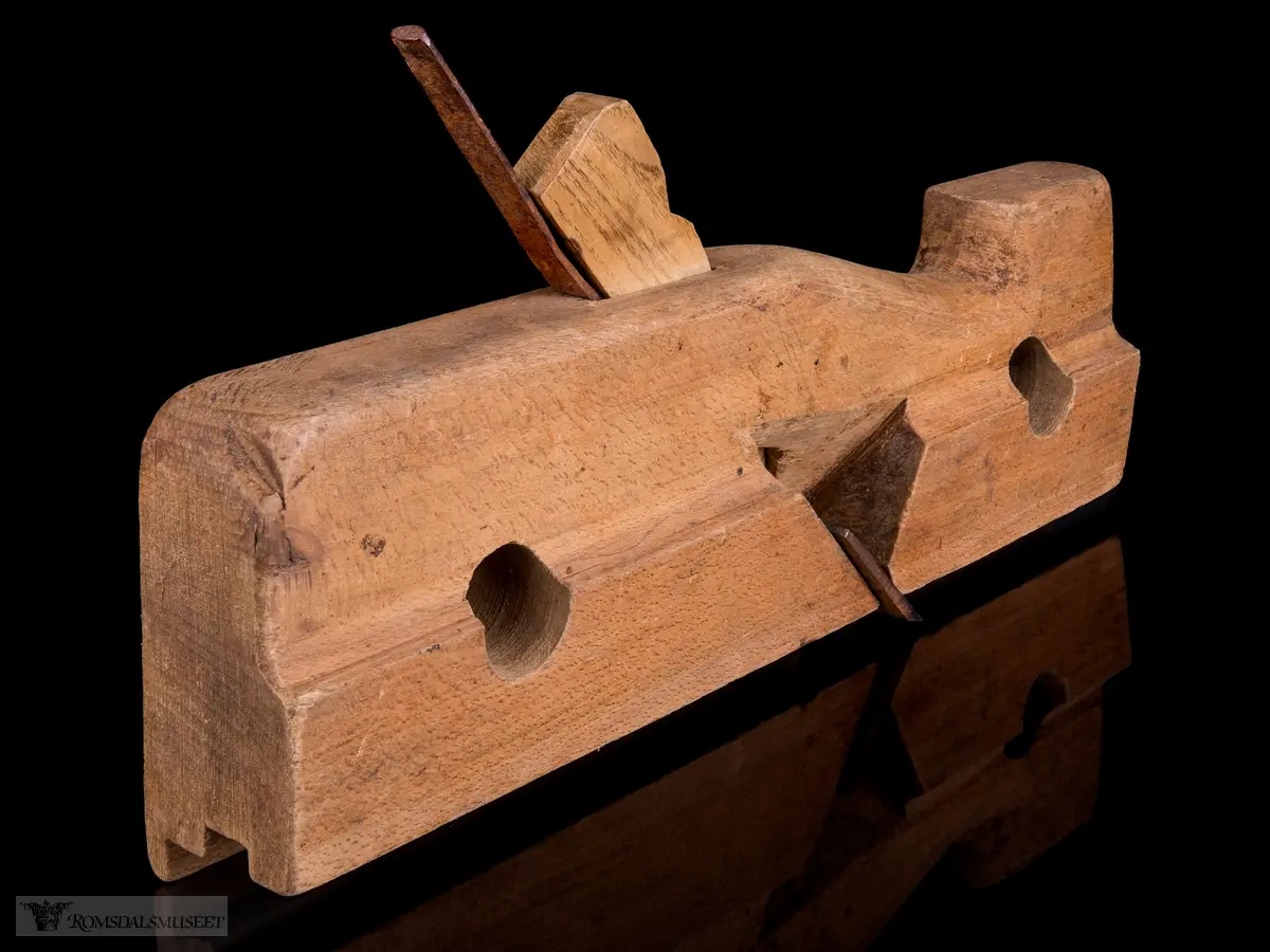 Smal rektangulær høvelstokk med tilskåret horn i forkant og avrundede hjørner. To gjennomgående opphengshull. Stokken er skåret slik at det er en støttekant ved siden av sålen. Gaffelformet høvelblad der et spor går langs sålen mellom de to tennene for høvling av fjær.