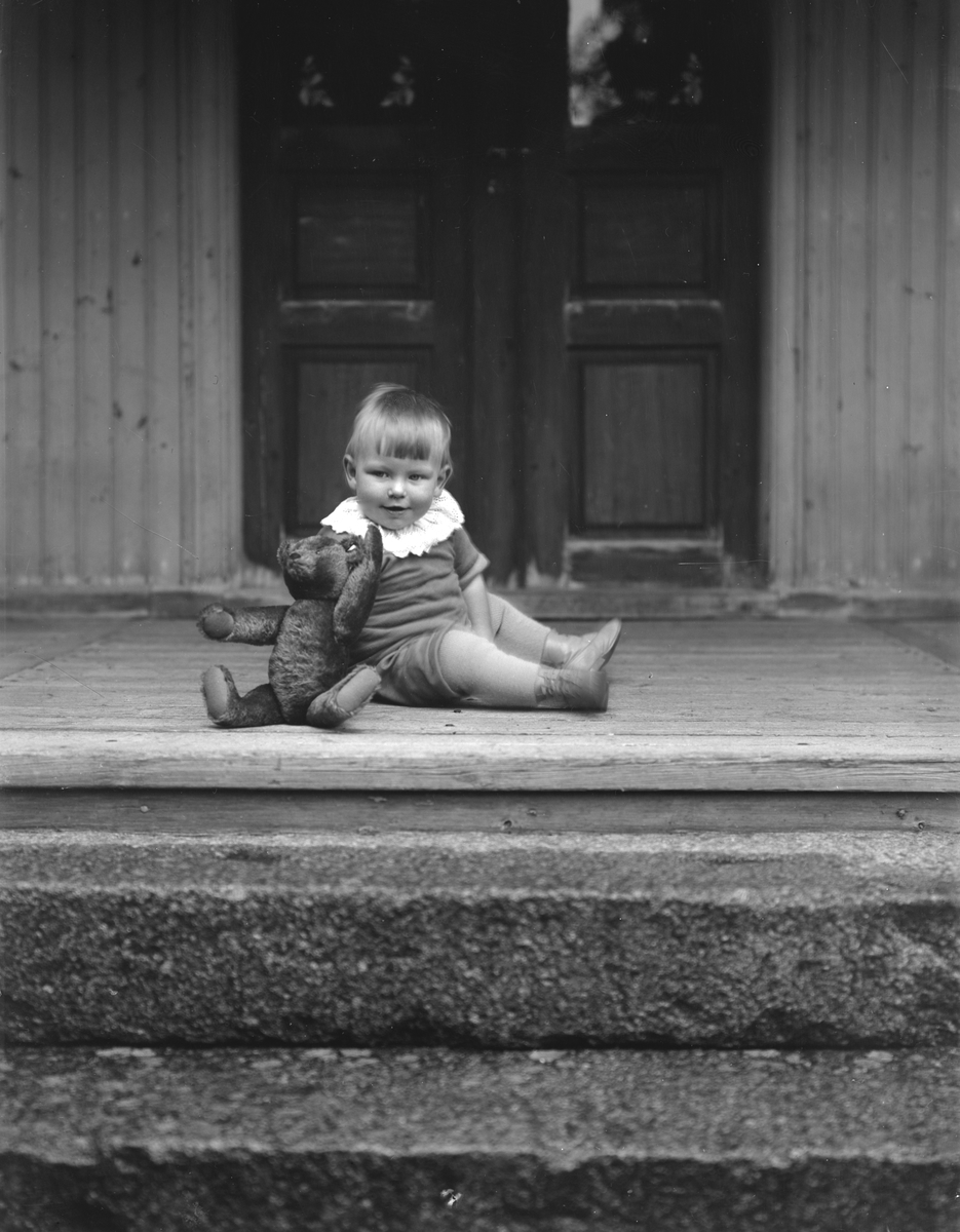 Åke Lindgren med sin älskade nalle på trappan till Födekulla i Svinhult. Vid tiden för bilden arrenderade föräldrarna gården. Åke blev dock faderslös i sjuårsåldern och familjen bröt upp och flyttade till Ingatorp 1935.