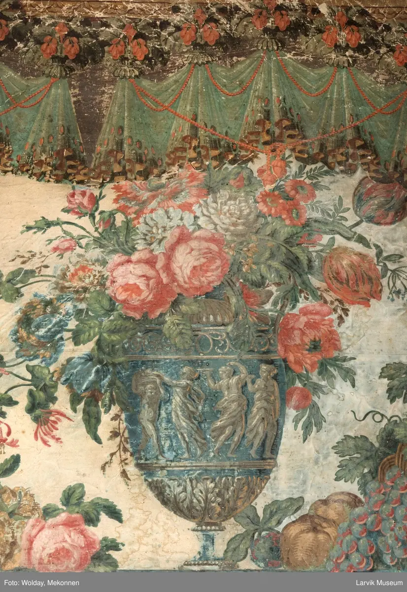 |Tapeten er påmalt tapetborder og brystning. Fra Hovland gård i Larvik.
Den øverste, brede borden: Gerlander/draperi med blomsterranker.
Den nederste, smalere borden: Tekstilbord med blomster. Øver døren til høyre: Stillebenmotiv med blomster og frukt.