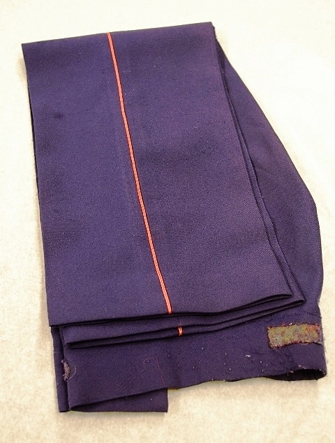 Jakke (a): blå polyester med for av blå kunstsilke. Rød krage og slag. 3 blanke knapper. Lyremotiv. Epauletter på skuldrene: rød, flettet silkesnor med blank knapp. Rød silkesnor rundt høyre skulder. Påsydde merker: norsk flagg, Mjøsegnenes krets, Gjøvik; Vindingstad skolekorps med logo
Bukse (b): blå polyester, røde render i sidesømmene. Nylon glidelås i gylfen. 1 blå plastknapp
Magebelte (c), rødt, blankt kunstfiberstoff, foret med rød bomull. 3 folder midt på. Lukkes med borrelås. 75 l, 12 b
Pyntesløyfe (d), samme tøy som beltet. Røde frynser i nedkant. Kan festes med borrelås til belte.  41 l, 12 b.