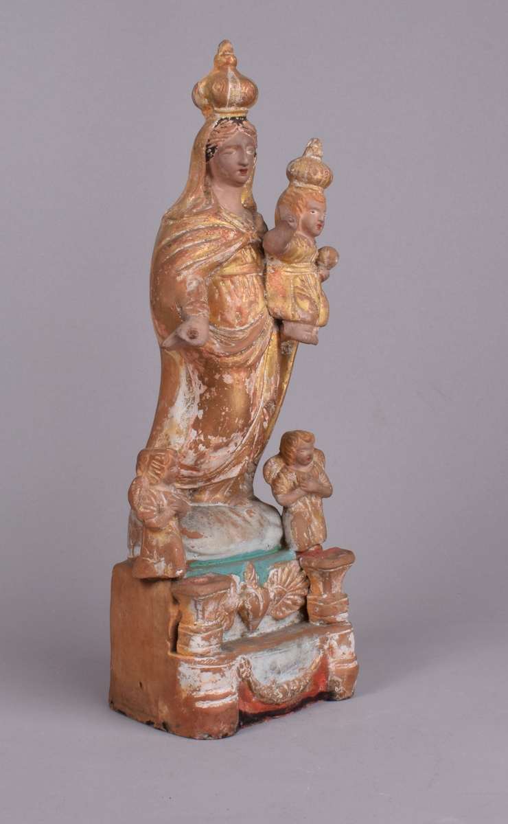 Maria med Jesusbarnet på armen. Begge med kroner. 2 små engler ved Marias føtter.