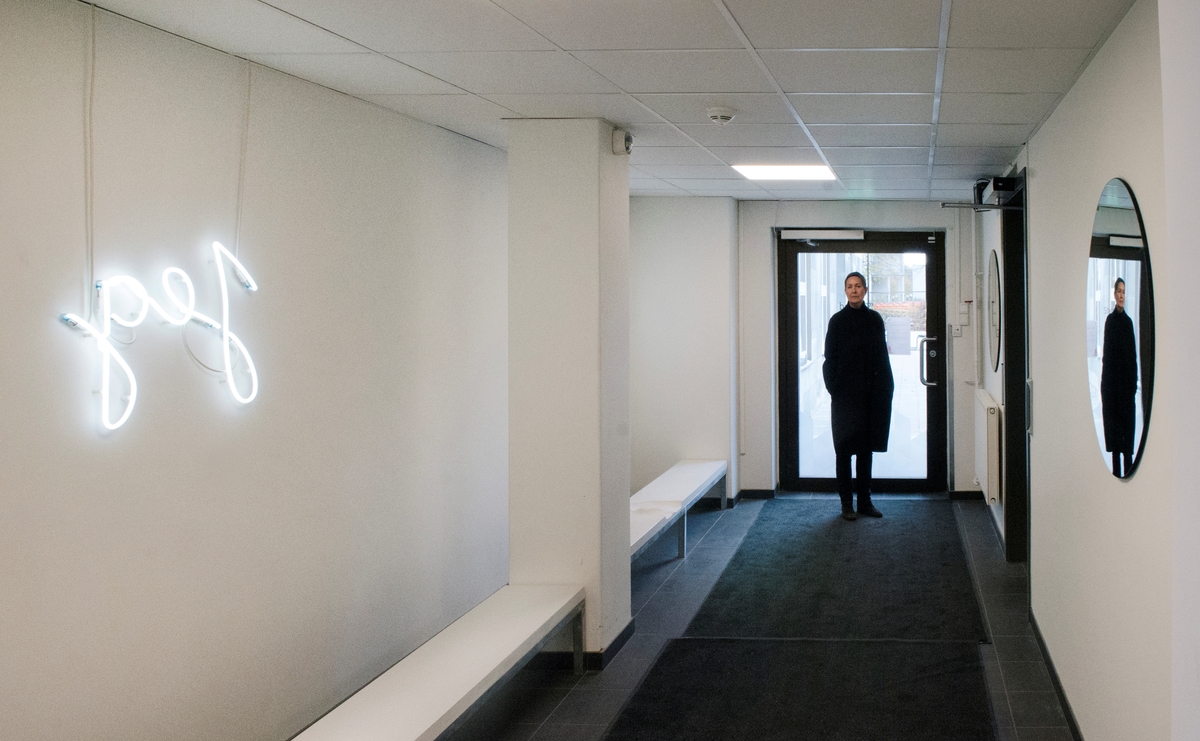 Christensens verk er ein installasjon med to benkar av stål. Benkane er dekt med lys betong kor det er laga avtrykk av menneskekroppar som har sete der. Over kvar benk heng eit kvitt neonrør forma som ordet «jeg». På veggen bak heng det ein rund spegel, slik at begge neonarbeida blir spegla på motståande vegg.

Kunstverket er mogeleg å oppleve også for dei med synshemming, både på grunn av det sterke lyset i neonrøra og fordi det kan utforskast med hendene. Det inviterer til sansing, leik og refleksjon rundt kva det er å vere eit «eg». Spegelen minner om kor viktig spegling i bokstaveleg og overført tyding er for kjensla av kven ein er, og korleis identitet endrar seg over tid. Avtrykka på benkane er i ulik storleik, så ein kan setje seg i dei og kjenne etter om ein passar inn – eller berre sjå på kunsten på motsett side.