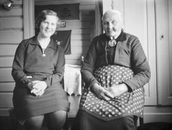 To kvinner sitter inne. Til høyre med forkle, fru banemester