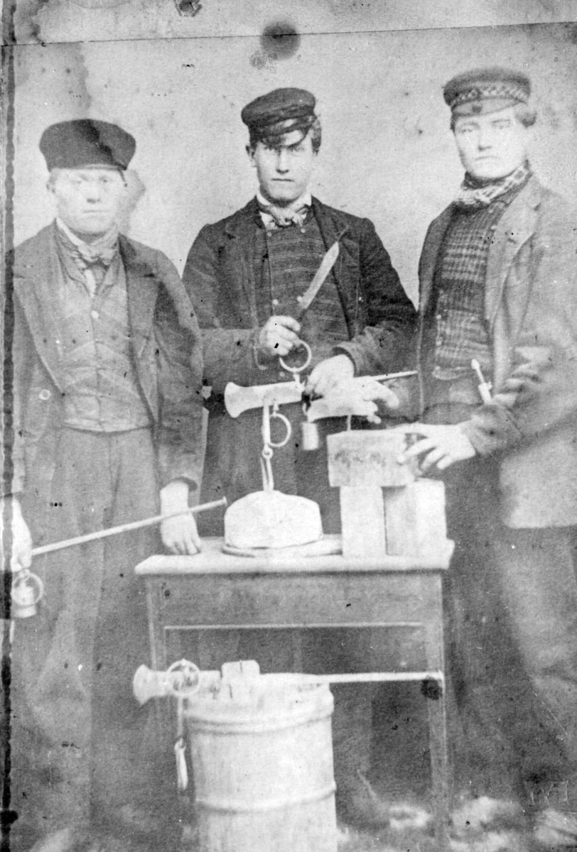Repro: Tre menn med bismervekt, selger smør og ost på Kirstiaina Torg, f.venstre: H.Gompholen, P. Sveipe, G. Bystadløkken