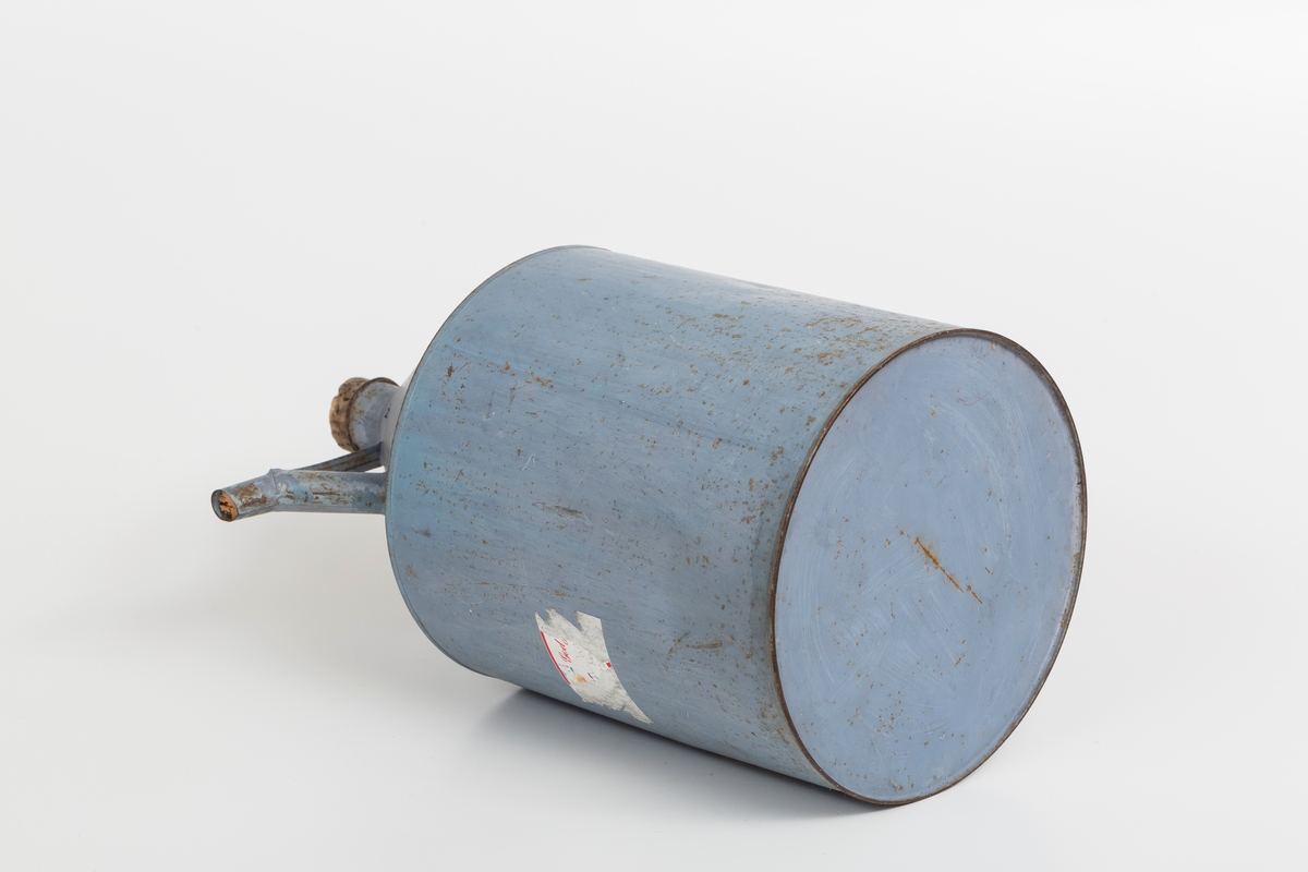 Kanne i sink, blå. Korket i tuten og korklokk med plast. Har håndtak og helletut. Kannen har påklistret god jul merkelapp med navn. Delvis avrevet.