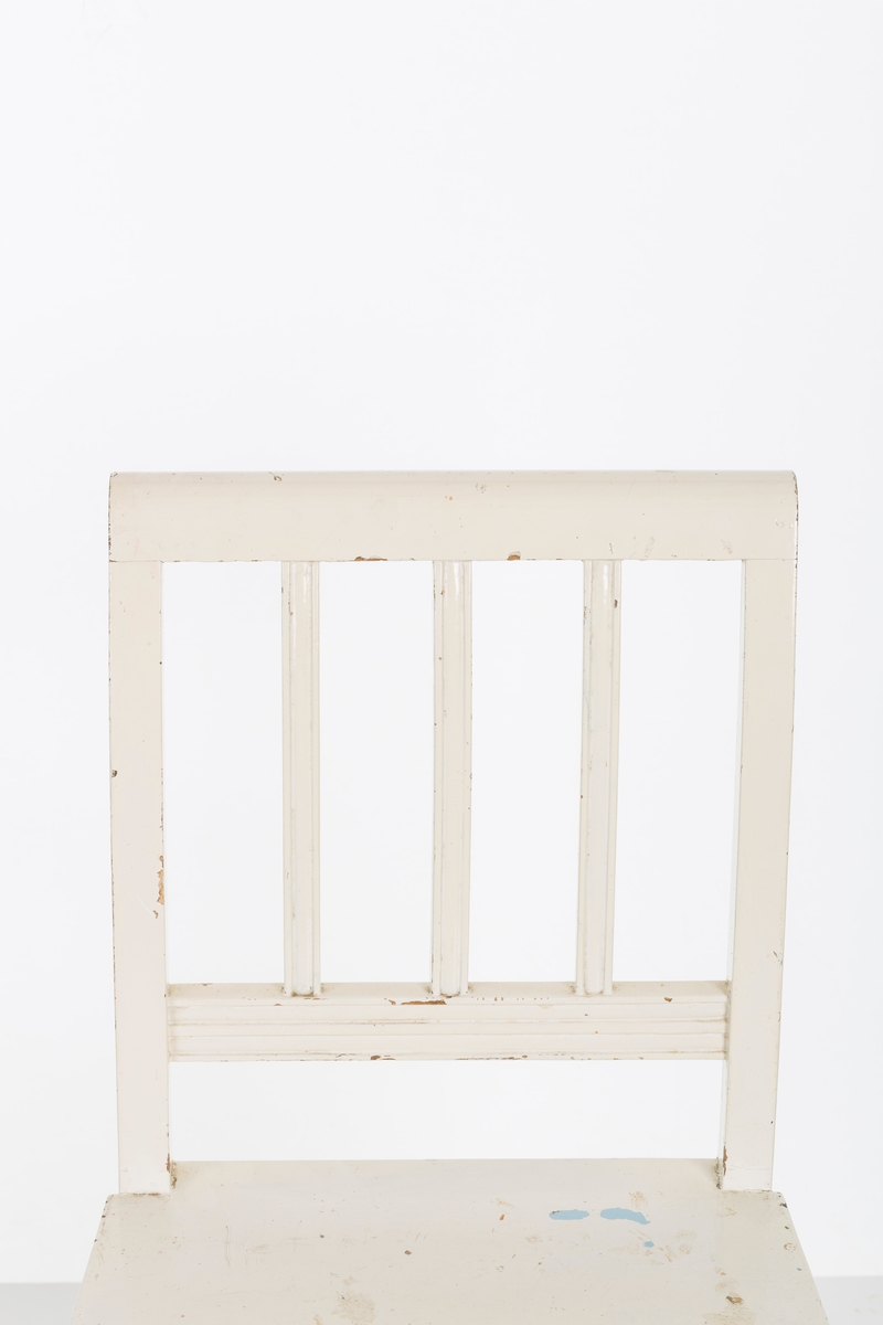 Hvitmalt spisestuestol. Sprosser i rygg og mellom stolbeina på venstre og høyre side.