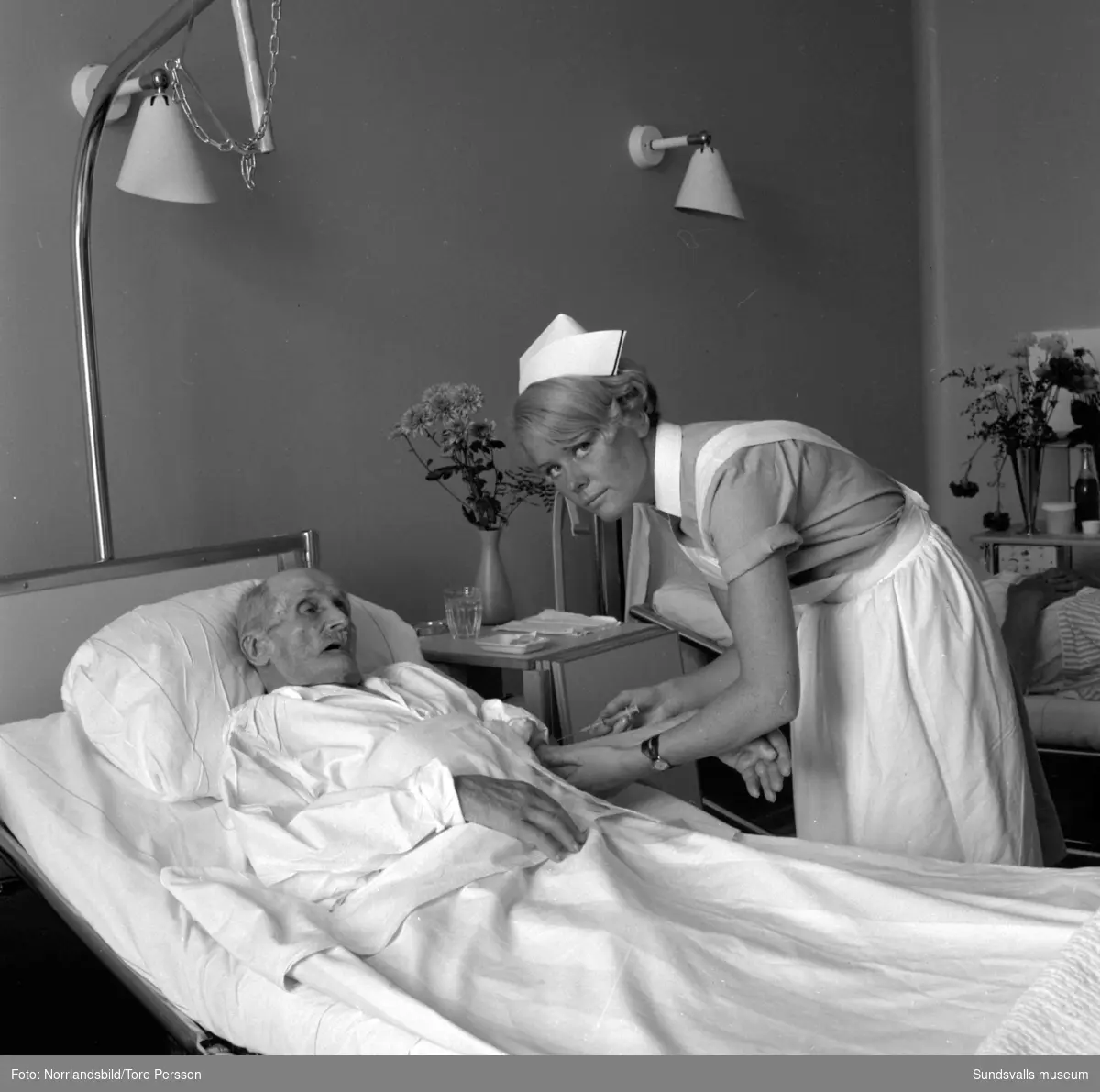 Sjuksköterskeskolan i Sundsvall. Två elever förbereder medicin till patienterna. En gammal man får en injektion.